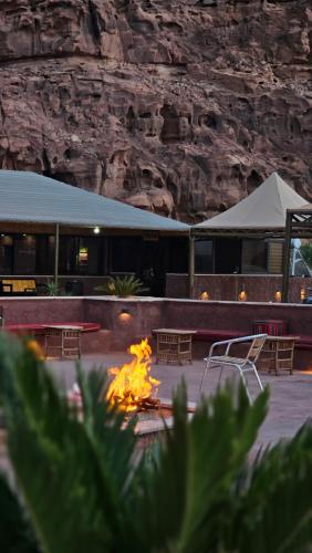 a fire pit with tables and chairs in front of a building at RUM ROYAL FLOWER lUXURY CAMP in Wadi Rum