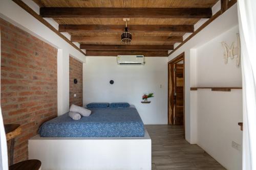 a bedroom with a bed and a brick wall at Ganso & Búho in Ayampe