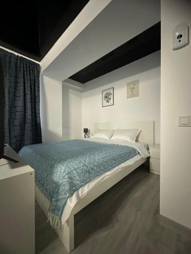 a bedroom with a large bed with a blue comforter at Promenada Apartments in Năvodari
