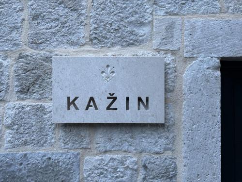 a sign on the side of a stone wall at KAŽIN supreme in Kotor