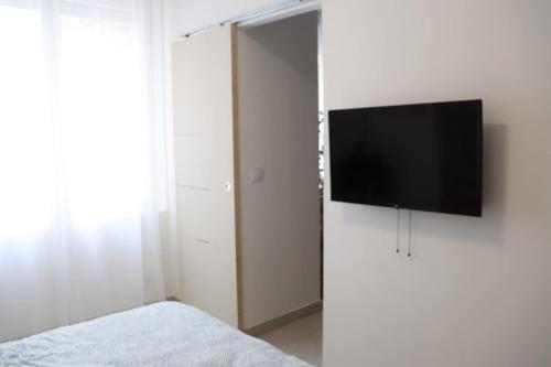 a bedroom with a flat screen tv on a wall at Loveroom Mykonos avec balnéothérapie in Toulon