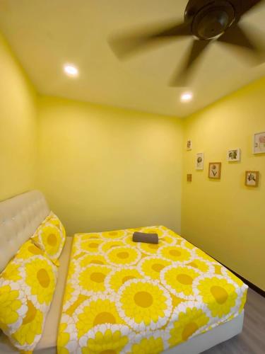 a yellow bedroom with a bed with a flower blanket at PulauKetam HuaHeeHomes 吉胆岛欢喜亲子民宿 in Bagan Teochew
