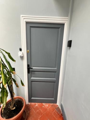 une porte grise avec une plante en pot à côté dans l'établissement Studio Proche Toutes Commodités, à Perpignan