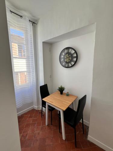 une salle à manger avec une table, des chaises et une horloge dans l'établissement Studio Proche Toutes Commodités, à Perpignan