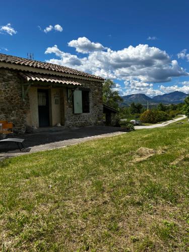 une maison en pierre avec une pelouse verdoyante devant elle dans l'établissement Le Gast, Vaumeilh, à Sisteron