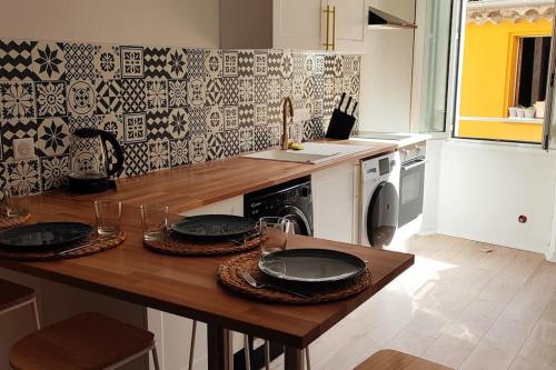 a kitchen with a wooden table with plates on it at Appartement en Plein Centre au Pied des Musées in Grasse