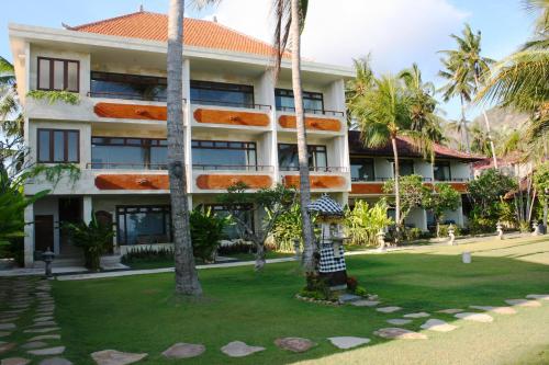 a building with palm trees in front of it at Hotel Genggong in Candidasa