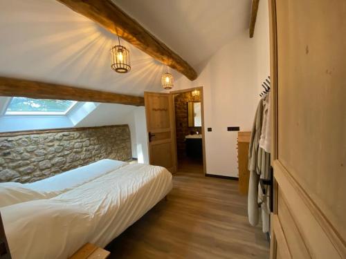 une chambre avec un lit et un mur en pierre dans l'établissement La maison de campagne, à Églisolles