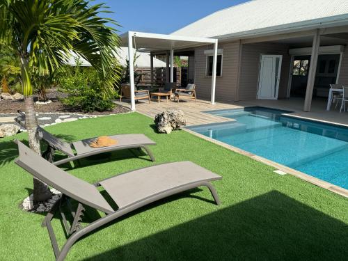 a yard with a pool and two chairs and a house at Nakolodge - 2 chambres -piscine et jardin privatifs in Sainte-Anne