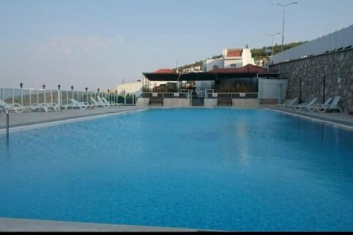 ein großer blauer Pool mit Stühlen und ein Gebäude in der Unterkunft Karaburun'da Yeni Tripleks BegonVİL-LA in Izmir