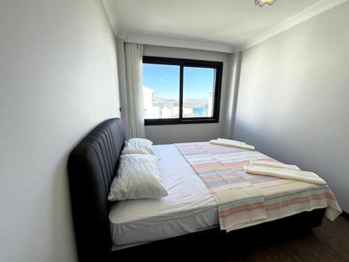 a small bedroom with a bed with a window at Karaburun'da Yeni Tripleks BegonVİL-LA in Izmir