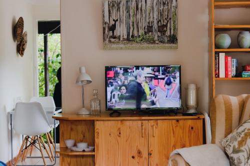 sala de estar con TV en un centro de entretenimiento de madera en Vista Garden Cottage, en Mbabane