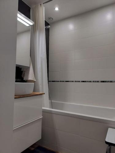 une salle de bain blanche avec une baignoire et une douche dans l'établissement La Ramure, maison de village, à Allanche