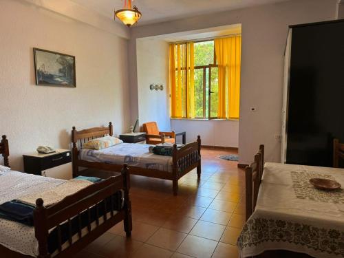 a room with three beds and a window with yellow curtains at Hotel brazil in Peshkopi