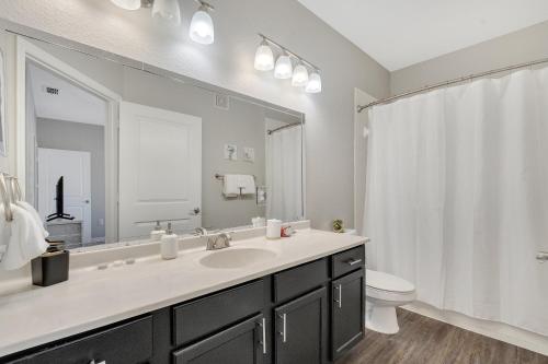 a bathroom with a sink and a toilet and a mirror at Luxury 3bd, 2bath, universal studios in Orlando