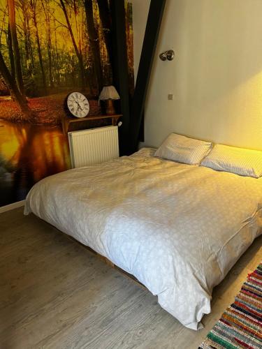 een bed in een slaapkamer met een klok aan de muur bij Le Gast, Vaumeilh in Vaumeilh