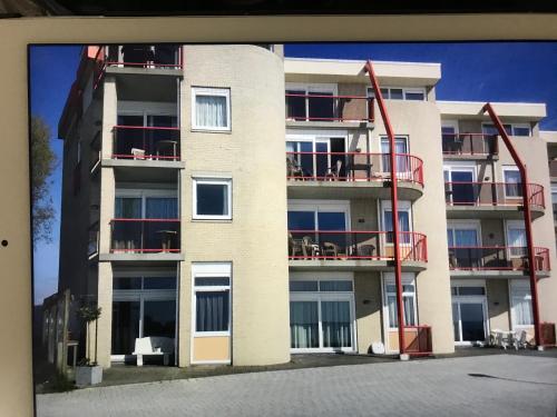 a tall white building with red balconies on it at Appartement Zuiderzeestate Makkum in Makkum