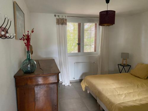 sypialnia z łóżkiem i stołem z wazonem w obiekcie Appartement en Provence-Lubéron - piscine et calme w mieście Volx