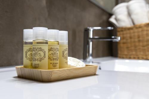 un groupe de trois bouteilles de liquide jaune posées sur un lavabo de salle de bain dans l'établissement Casa da Cruz Alta, à Seia