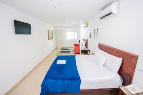 a bedroom with a bed and a couch and a television at Hotel Chayrama in Santa Marta