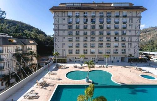 a hotel with a swimming pool in front of a building at Flat 205 completo no Granja Brasil em Itaipava in Petrópolis