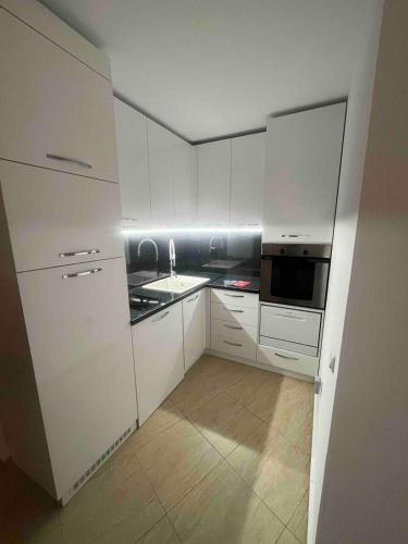a kitchen with white cabinets and a sink and a microwave at Apartment in Sunny beach, Complex Sun Village, 80 qm, 2 bedrooms & living room near to the beach, SWIMMING POOL, garden in Sunny Beach