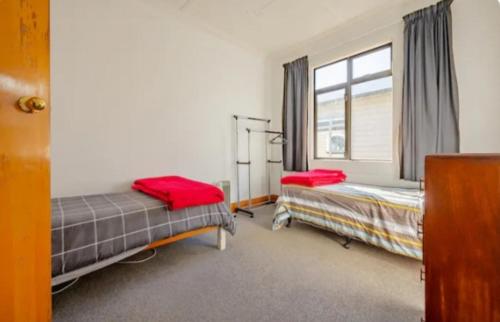 1 dormitorio con 2 camas y ventana en St Clair Holiday House, en Dunedin