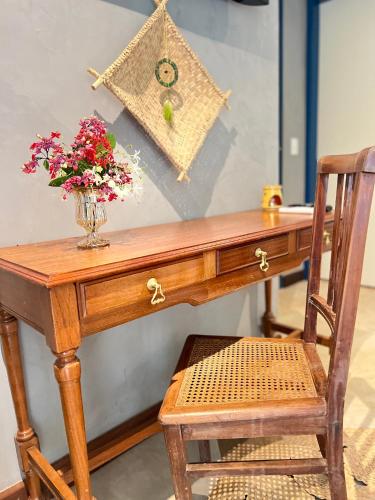 a wooden desk with a vase of flowers and a chair at Villa Lulu Geribá in Búzios
