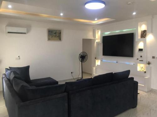 Una sala de estar con un sofá y un televisor de pantalla plana. en BJ's SHORTLET OGOMBO ROAD, en Lagos