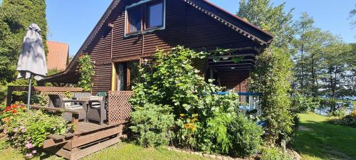 a wooden cabin with a bench and a garden at Domek rustykalny z sauną nad samym jeziorem in Leleszki