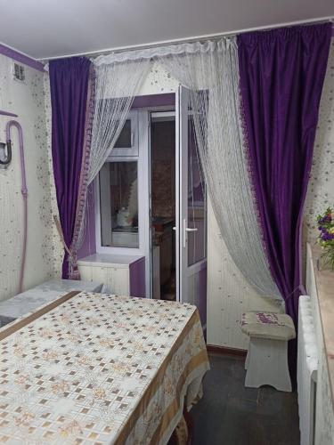 Schlafzimmer mit einem Bett mit lila Vorhängen in der Unterkunft Трешка Саулет 11 in Qysylorda