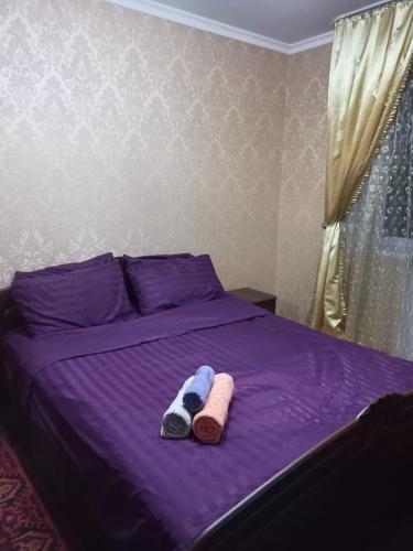 ein violettes Bett mit zwei Handtüchern darüber in der Unterkunft Трешка Саулет 11 in Qysylorda