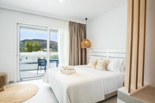 um quarto com uma cama branca e uma varanda em Alkithea luxury suites em Cárpatos