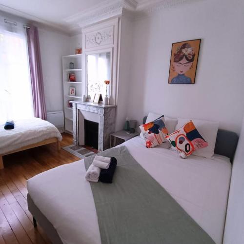 - un salon avec deux lits et une cheminée dans l'établissement Authentic Parisien Suite -Paris historique/Metro, à Saint-Ouen