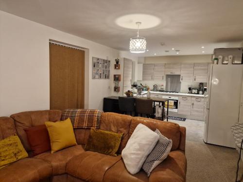 a living room with a brown couch and a kitchen at A stunning room in a 2 bed apartments in the heart of Medway in Gillingham