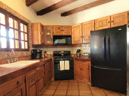 cocina con armarios de madera y nevera negra en Spanish Style Vacation Home in Rosarito, en Primo Tapia