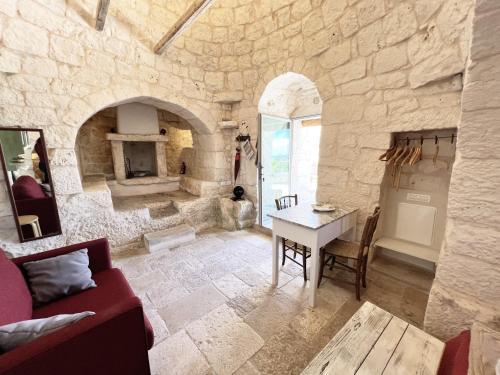 ein Wohnzimmer mit einem Tisch und einer Steinmauer in der Unterkunft Trullo fiore in Ostuni