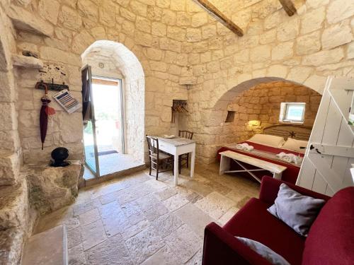 a bedroom with a bed and a desk in a stone wall at Trullo fiore in Ostuni