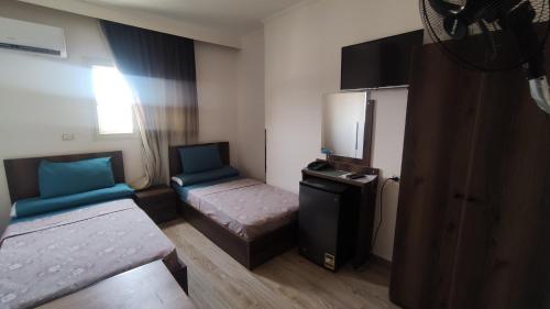 Habitación pequeña con 2 camas y nevera pequeña. en فندق أجياد Agyad Hotel, en Asiut