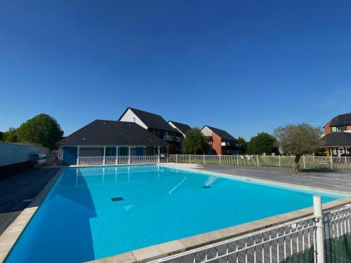 a large blue swimming pool with houses in the background at Sweet Dreams in Honfleur