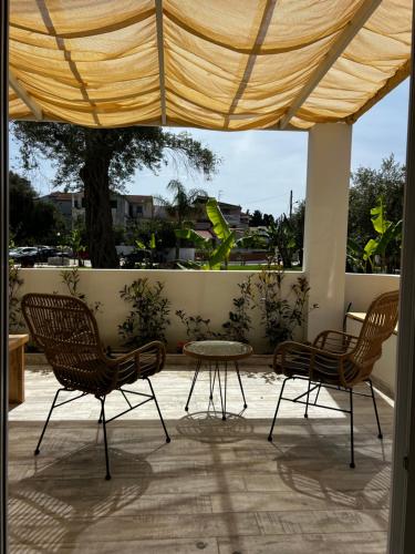 a patio with two chairs and a table and a window at Greco Mare in Kavos