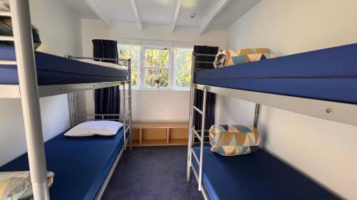 Hekerua Lodge Backpackers Hostel Waiheke Island في Oneroa: غرفة بسريرين بطابقين ونافذة