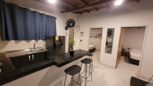 a kitchen with a sink and two bar stools at La Familia Hostel - Manila in Medellín