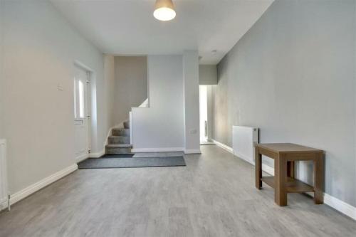 ein leeres Zimmer mit einer Treppe und einem Tisch in der Unterkunft Newly renovated private house in Portsmouth