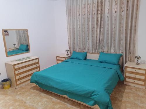 a bedroom with a blue bed and a mirror at Yaso Roof & Apartments in Amman