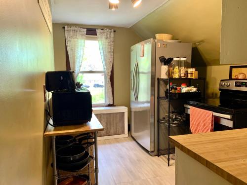 a kitchen with a refrigerator and a table with a microwave at Cozy 2nd Floor Apartment With Private Entrance in Chicopee