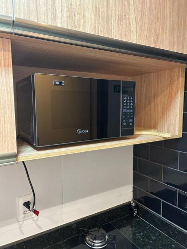 a microwave on a shelf in a kitchen at STUDIO PORTO PRIME PREMIUM in Porto De Galinhas