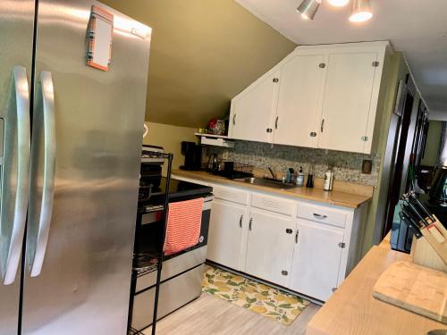 cocina con armarios blancos y nevera de acero inoxidable en Cozy 2nd Floor Apartment With Private Entrance, en Chicopee