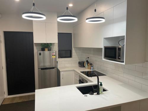 a kitchen with white cabinets and a stainless steel refrigerator at Flat Bush Holiday Accomodation in Auckland