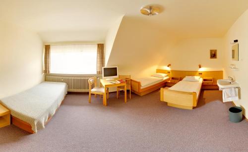 a hotel room with two beds and a desk at Pension Keinath in Stuttgart